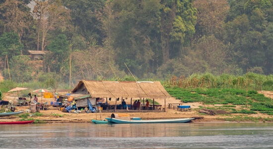 Pak Ou’s tranquil Mekong cliffs in Laos on a Pak Ou Tours banner by Legend Travel Group.